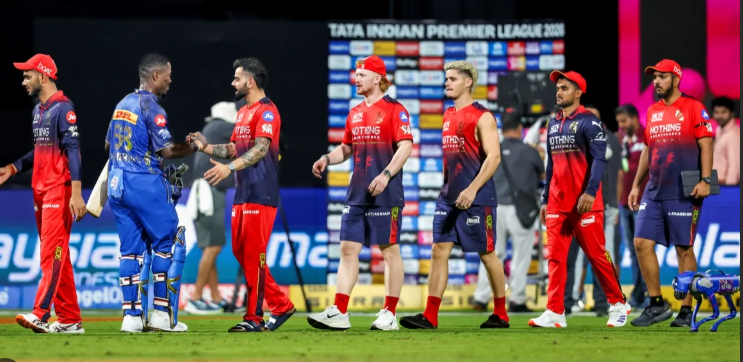 RCB और मुंबई इंडियंस के खिलाड़ी IPL मैच के बाद मैदान पर एक-दूसरे से हाथ मिलाते हुए, बैकग्राउंड में प्रेजेंटेशन एरिया दिखाई दे रहा है।